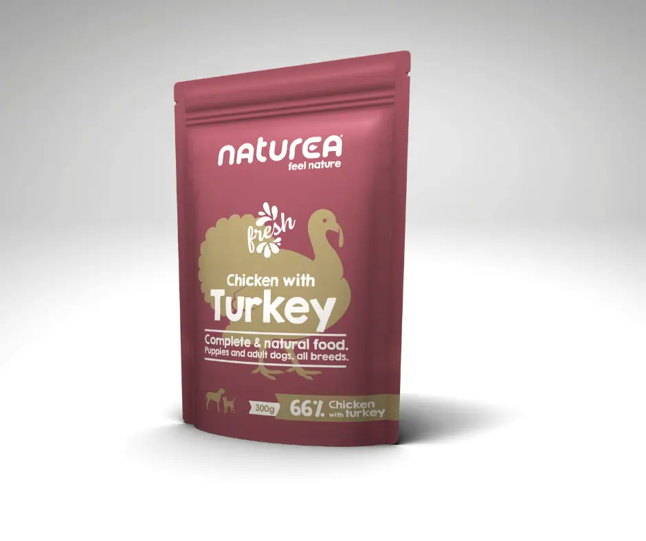 Sachet de pâtée Naturea Poulet Dinde pour chiens, posé sur un fond gris clair.
